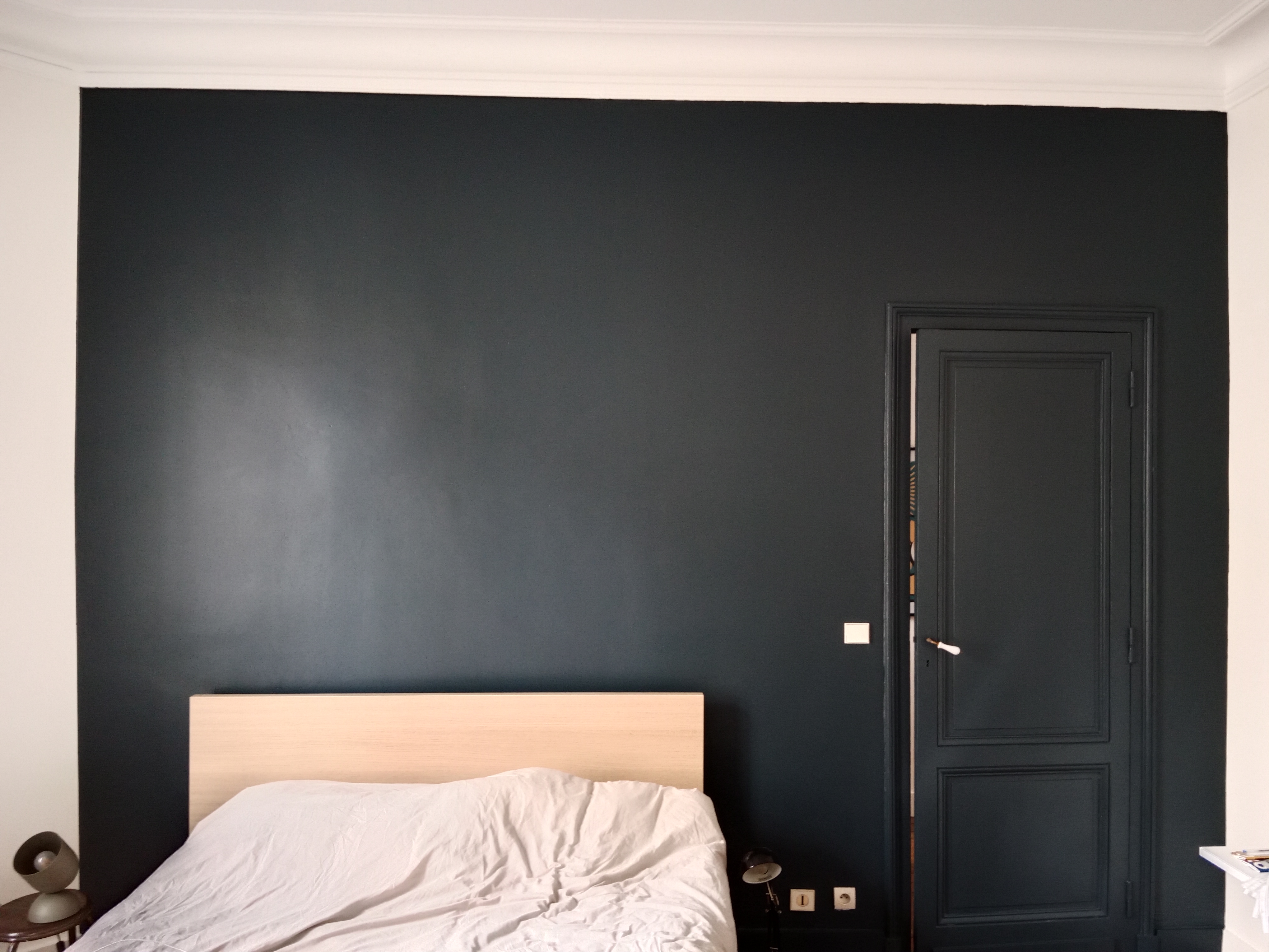 Chambre avec mur peint en bleu foncé et porte assortie, moulures blanches